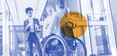 Female in a wheelchair having a discussion with her colleagues in a foyer